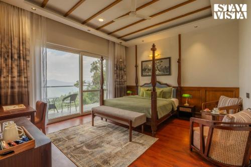 a bedroom with a bed and a large window at StayVista at The Cloudberry Crest with BBQ & Bonfire in Rāmgarh
