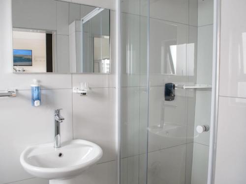 a white bathroom with a sink and a shower at Queens Cove in Lüderitz