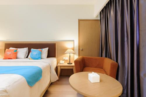 a hotel room with a bed and a chair and a table at SANS Vibes d Grande Hotel Batam in Nagoya