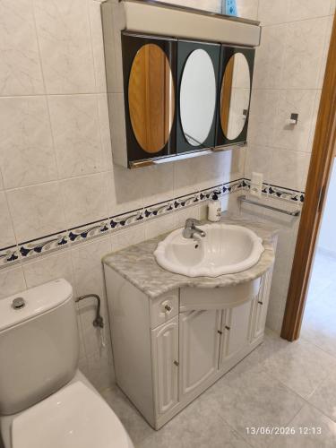 a bathroom with a toilet and a sink and two mirrors at ADOSADO Avda BREOGAN 71 in Foz