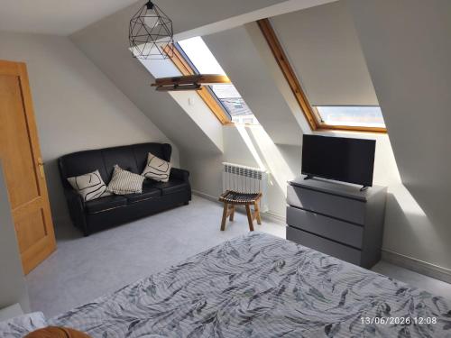 a bedroom with a couch and a tv in a attic at ADOSADO Avda BREOGAN 71 in Foz