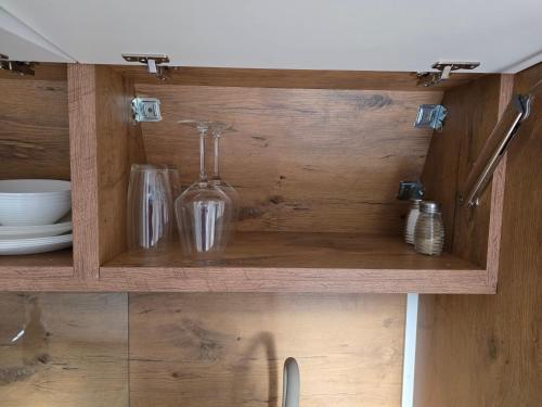 a wooden cabinet with glasses and bottles on it at Doune House Pods in Beauly