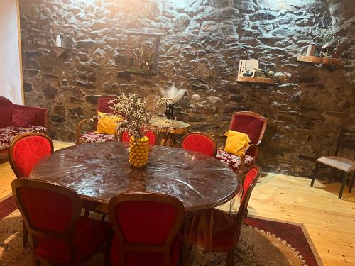 a table and chairs in a room with a stone wall at Qedani in Ch'k'valeri