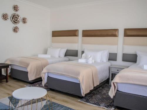 a room with three beds and a table at Queens Cove in Lüderitz
