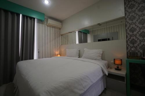 a bedroom with a large white bed and a mirror at Townhouse Oak Hotel Damar Kurung in Gresik