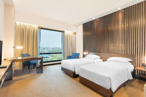 a hotel room with two beds and a desk and a television at Hyatt Raipur in Raipur