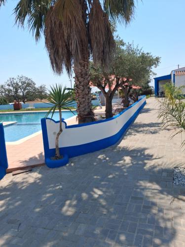 a row of palm trees next to a swimming pool at Nefama Pensao in Ourique
