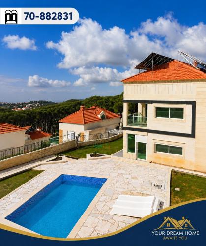 a house with a swimming pool in front of a house at Villa K تلة الصنوبر in Ḩāşbayyā