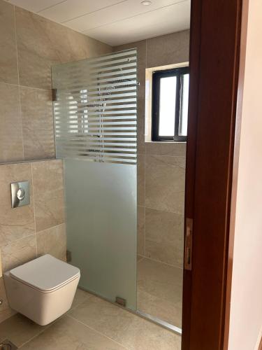 a bathroom with a toilet and a glass shower at Villa K تلة الصنوبر in Ḩāşbayyā