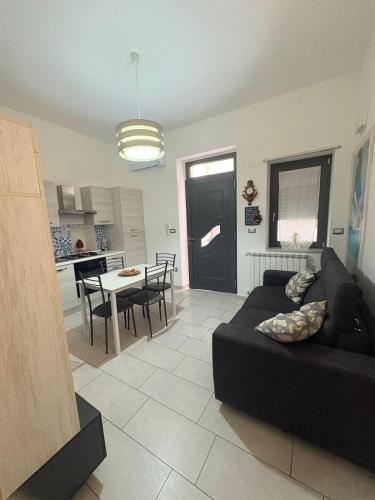 a living room with a black couch and a kitchen at Il gingillo di Alice by Maniel Beach Hotel in Letojanni