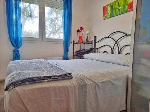 a bedroom with two beds with blue curtains and a window at Villa Eucaliptus Lloret de Mar in Vidreres