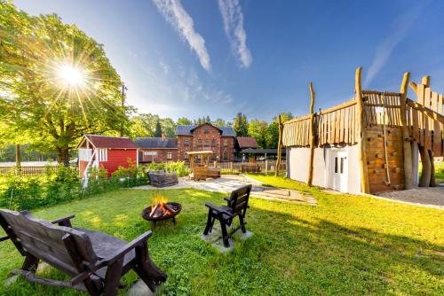 a yard with two benches and a fire pit at Ferienhaus Bimmelbahn 2 - Familienferienhaus 100 m am Dampflokbahnhof Sauna Trampolin Spielezimmer in Olbersdorf