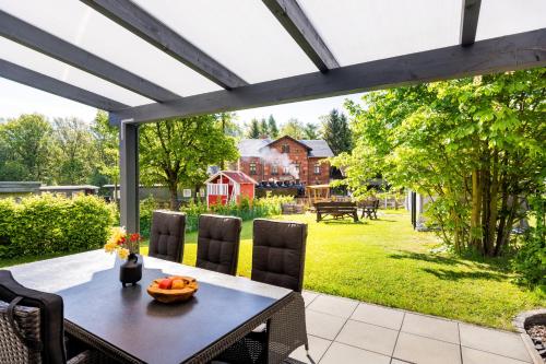 a patio with a table and chairs and a view of a yard at Ferienhaus Bimmelbahn 2 - Familienferienhaus 100 m am Dampflokbahnhof Sauna Trampolin Spielezimmer in Olbersdorf