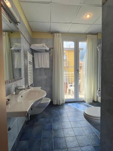 a bathroom with two sinks and a tub and a window at Hotel La Terrazza in Porto San Giorgio