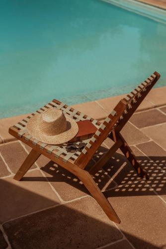 a straw hat sitting on a bench next to a swimming pool at Moulin de Longuecoste, 11 couchages, Nature, Rivière, Piscine et Pool House in Montet-et-Bouxal
