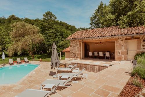 a patio with chairs and a pool and a building at Moulin de Longuecoste, 11 couchages, Nature, Rivière, Piscine et Pool House in Montet-et-Bouxal