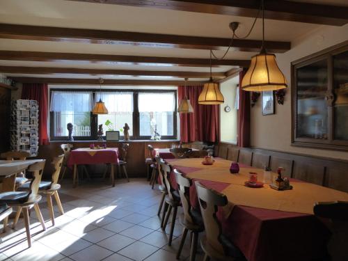 a dining room with tables and chairs and windows at Gasthaus Sonne in Wenns