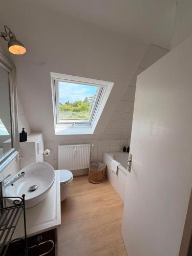 a bathroom with a sink and a toilet and a window at HYGGE HOMES - Apartment 'hyggehus' in Lüneburg