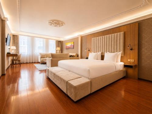 a bedroom with a large white bed and a couch at Chasse Boutique Hotel in Amsterdam