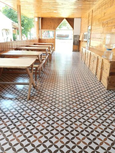 a restaurant with wooden tables and benches on a checkered floor at Nenapu Resorts in Oddarahalli