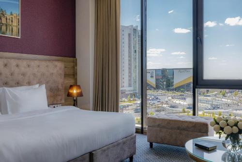 a hotel room with a bed and a large window at Ramada by Wyndham Shymkent in Shymkent