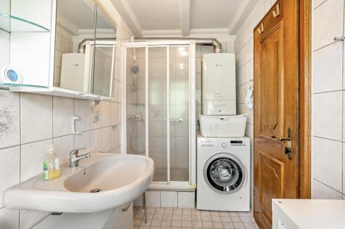 a bathroom with a sink and a washing machine at Ferienwohnung Rihm in Arrach