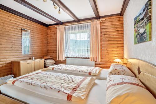 two beds in a room with wooden walls at Ferienwohnung Rihm in Arrach