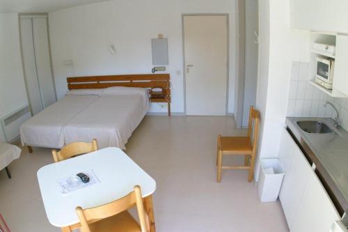 une petite pièce avec un lit, une table et des chaises dans l'établissement Résidence Augusta Réservé Seulement aux Curistes, à Dax