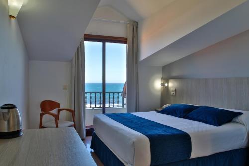 a bedroom with a bed and a view of the ocean at Hotel Restaurante Glasgow in Villadesuso