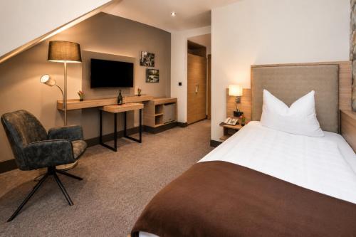 a hotel room with a bed and a chair and a desk at Kurhotel Grüttner mit eigenem Sole Thermal Schwimmbad 32 Grad und Saunalandschaft in Erwitte