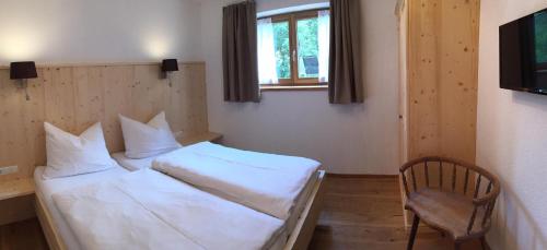 a bedroom with a white bed and a chair at Chalet Alte Mühle in Fügenberg