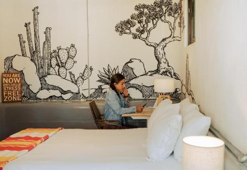 a woman sitting at a desk in a bedroom at Outsite Todos Santos - Formerly Perro Surfero Hotel Boutique in Todos Santos