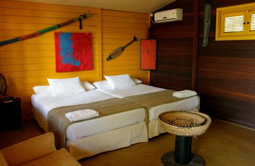 a bedroom with two beds and a chair in it at Pousada Cultural Canto dos Poetas in Aquiraz
