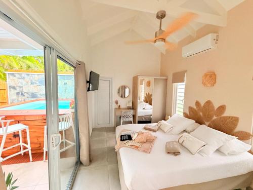 a bedroom with a bed and a balcony with a pool at Filao Cottage Bungalow avec Piscine Privée Proche plages in Sainte-Rose