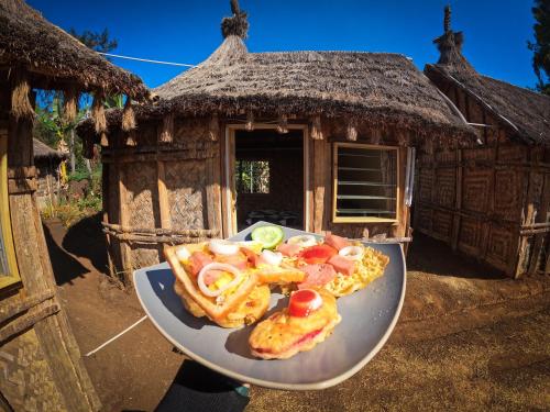 a plate of food on a table in front of a hut at Asaro Mudman Cultural Lodge in Goroka