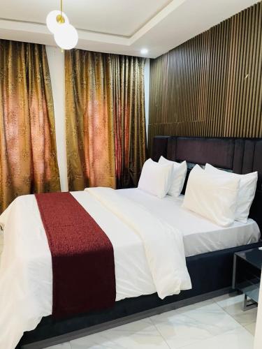 a bedroom with a large bed with white and red blanket at Soilsmart haven in Abuja