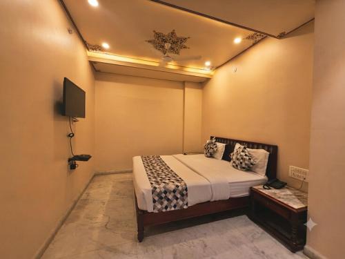 a bedroom with a bed and a tv on the wall at The Bayan Elegance Hotel in Jaipur