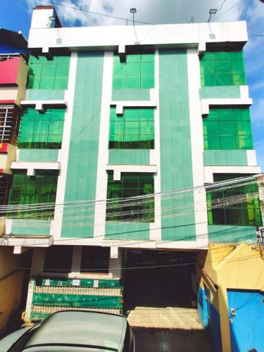 a building with green windows and a car parked in front at Hotel Eswara Temple Stay in Kumbakonam