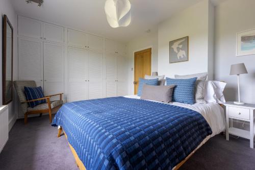 a bedroom with a blue bed and a chair at Forest View in Brockenhurst