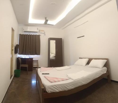 a bedroom with a bed and a desk in it at jambu's residence in Karūr