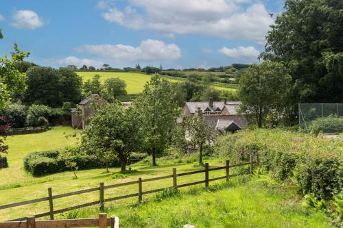 a farmhouse in a field with a fence at The Barn - Old Mill Cottages in Ilfracombe