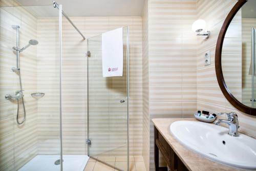 a bathroom with a shower, sink, and mirror at Mirage Medic Hotel in Budapest