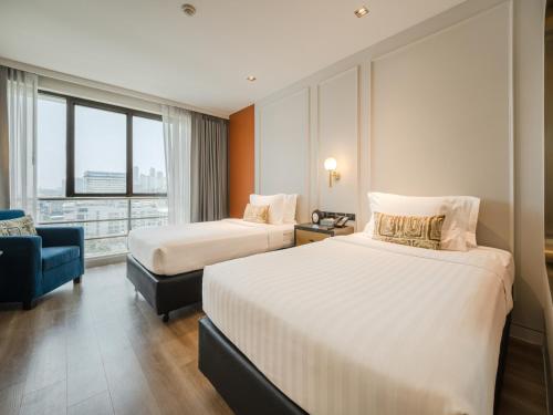 a hotel room with two beds and a blue chair at A-ONE Bangkok Hotel in Bangkok