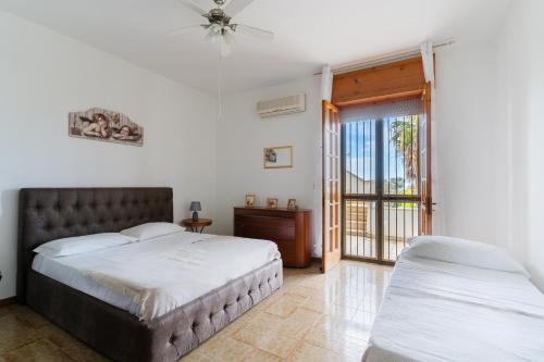a bedroom with two beds and a sliding glass door at Annamaria House by BarbarHouse in Marina di Mancaversa