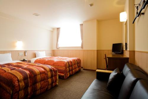 a hotel room with two beds and a couch at New Grande Mimatsu in Takamatsu