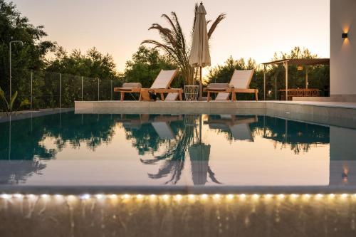 a swimming pool with two lounge chairs and an umbrella at Paradise Garden Villa in Moírai