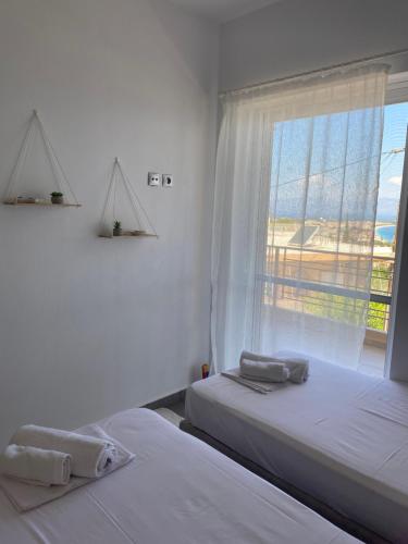 two beds in a white room with a window at Sunrise Summit in Egira