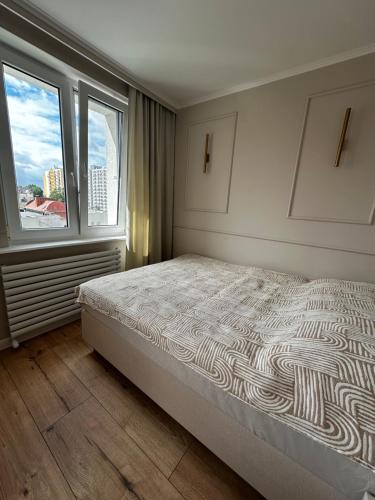 a bedroom with a large bed and two windows at Apartament KAJA in Malbork