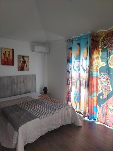 a bedroom with a bed and a window with curtains at LE PETIT PARADIS in Sainte-Rose