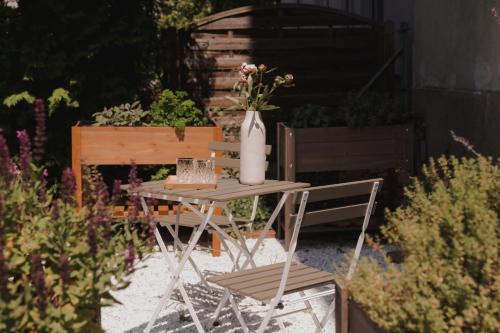 a table and chair in a garden with a vase of flowers at Oak House Vienna - Boutique Guesthouse near Meidling Station in Vienna